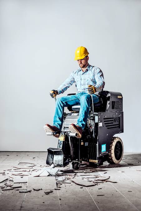 Operator riding a floor scraper over removed flooring.